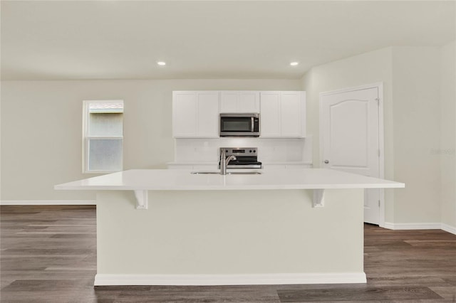 kitchen featuring sink, appliances with stainless steel finishes, white cabinetry, tasteful backsplash, and a center island with sink