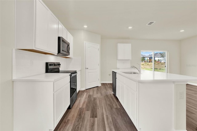 kitchen with sink, dark wood-type flooring, white cabinetry, stainless steel appliances, and a center island with sink