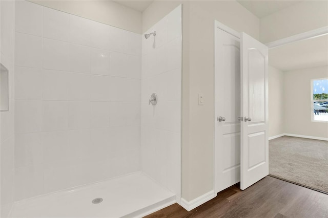 bathroom with tiled shower and wood-type flooring