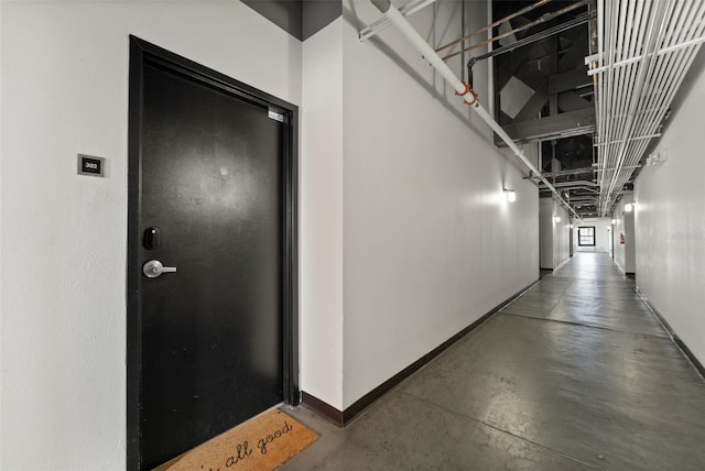 hall featuring concrete floors and baseboards