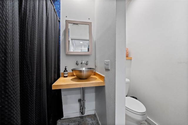 bathroom with baseboards, a sink, and toilet