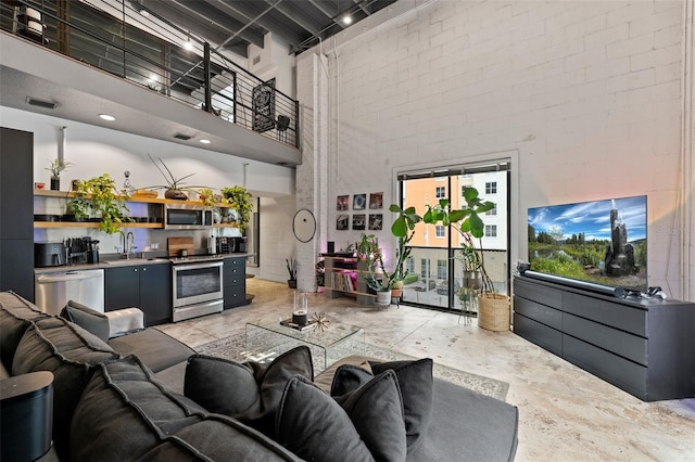 living area featuring concrete floors, brick wall, a high ceiling, and visible vents