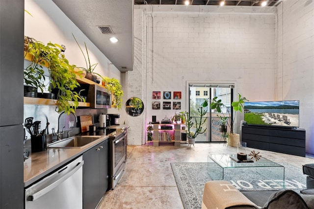 kitchen with brick wall, a sink, visible vents, appliances with stainless steel finishes, and open shelves