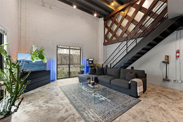 living area with concrete flooring, a high ceiling, and stairway