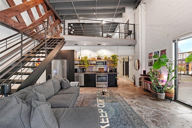 living room featuring stairs, a high ceiling, and concrete flooring