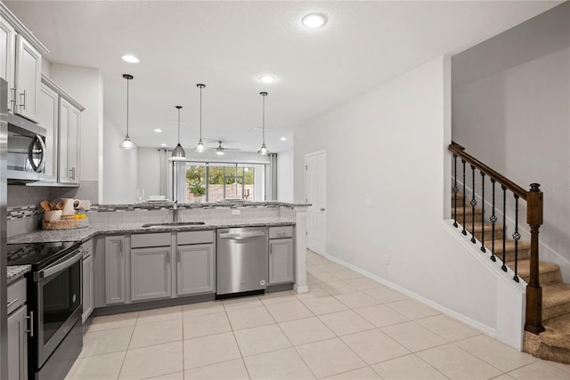 kitchen with stainless steel appliances, decorative light fixtures, gray cabinets, sink, and kitchen peninsula