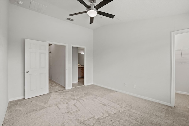 unfurnished bedroom featuring connected bathroom, light carpet, a walk in closet, and a closet