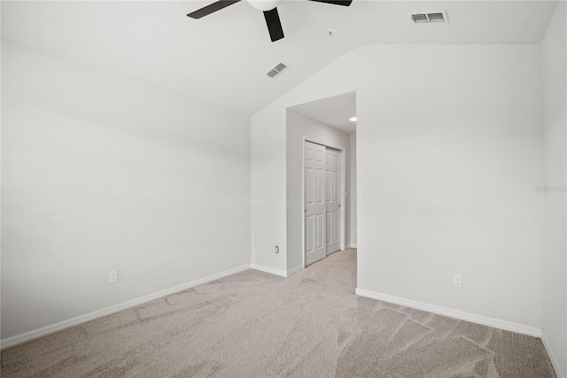 empty room featuring ceiling fan, vaulted ceiling, and light carpet