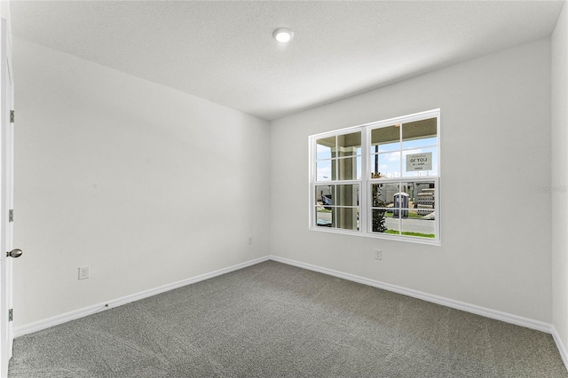 carpeted empty room featuring a textured ceiling