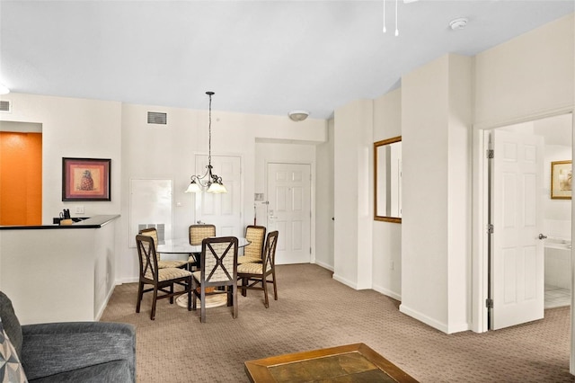 dining area featuring light carpet and a notable chandelier