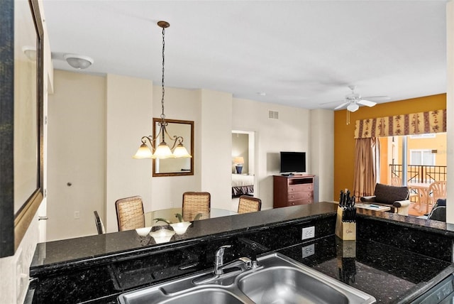 kitchen with pendant lighting, ceiling fan, dark stone counters, and sink