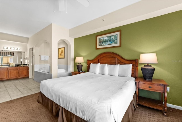 bedroom with connected bathroom, light tile patterned floors, and ceiling fan