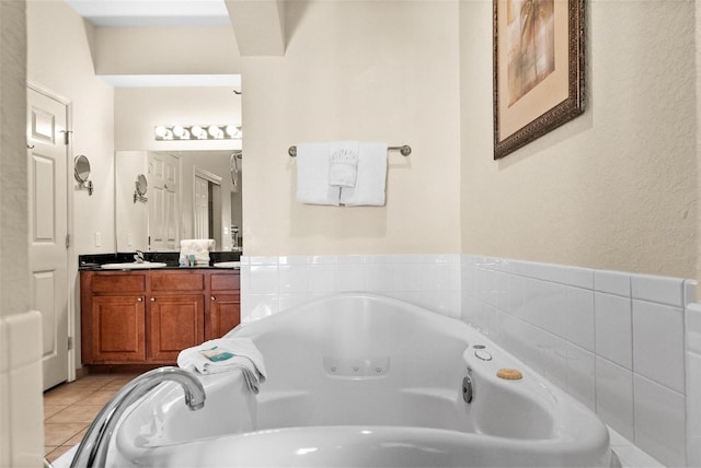 bathroom with a relaxing tiled tub, vanity, and tile patterned flooring