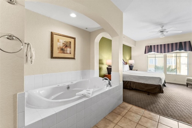 bathroom with tile patterned flooring, tiled tub, and ceiling fan