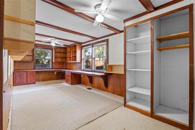 interior space with beamed ceiling, ceiling fan, plenty of natural light, and built in desk