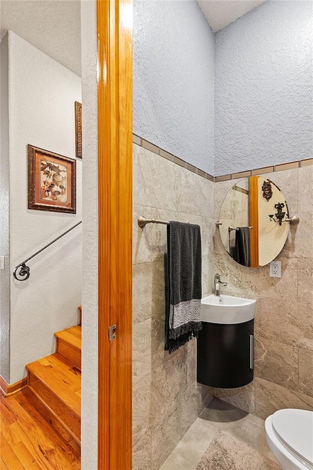 bathroom featuring vanity, wood-type flooring, tile walls, and toilet