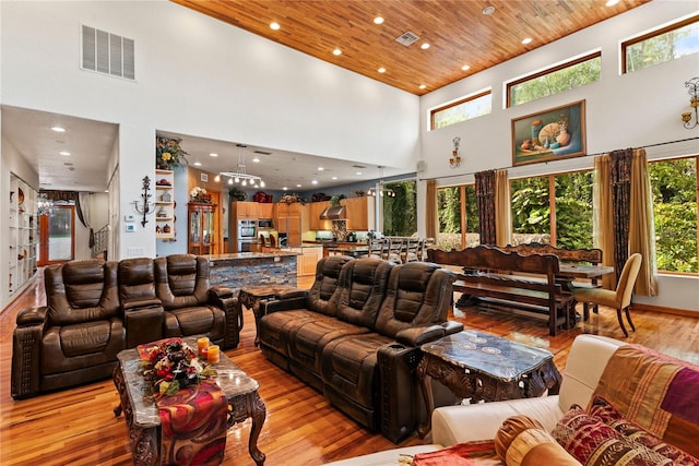 living room featuring a towering ceiling, light hardwood / wood-style floors, and wooden ceiling