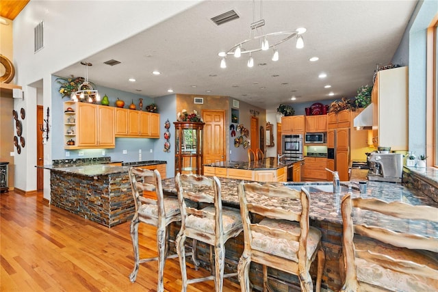 kitchen featuring built in appliances, hanging light fixtures, sink, and kitchen peninsula