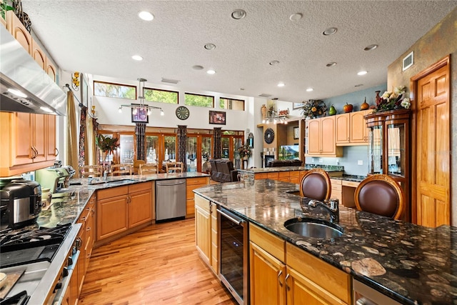 kitchen featuring sink, beverage cooler, exhaust hood, kitchen peninsula, and stainless steel appliances