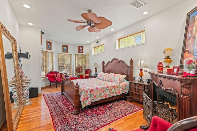 bedroom with ceiling fan, light hardwood / wood-style floors, and a textured ceiling