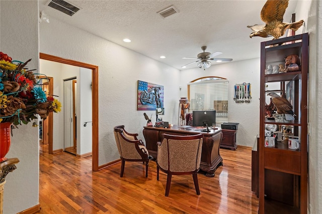 dining room with hardwood / wood-style floors, a textured ceiling, and ceiling fan