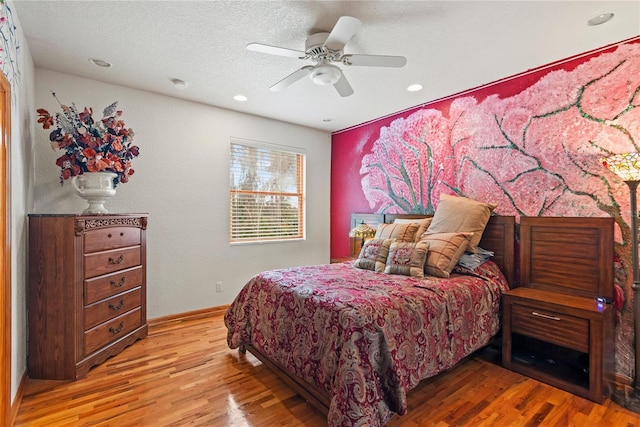 bedroom with ceiling fan, hardwood / wood-style floors, and a textured ceiling