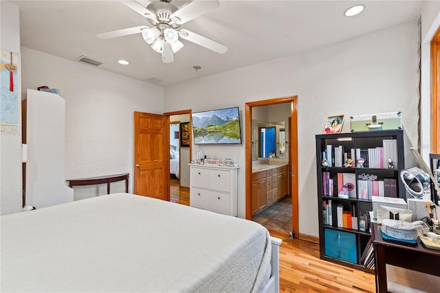 bedroom featuring ceiling fan, connected bathroom, and light hardwood / wood-style floors