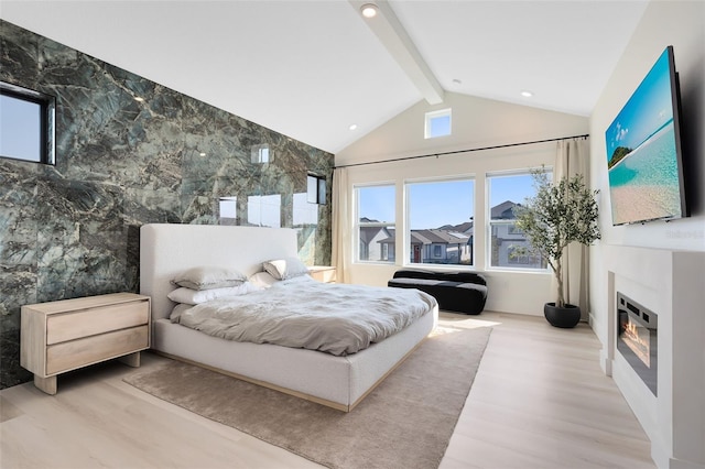 bedroom with vaulted ceiling with beams and light wood-type flooring