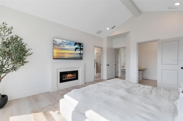 bedroom featuring beamed ceiling, ensuite bathroom, high vaulted ceiling, and light wood-type flooring