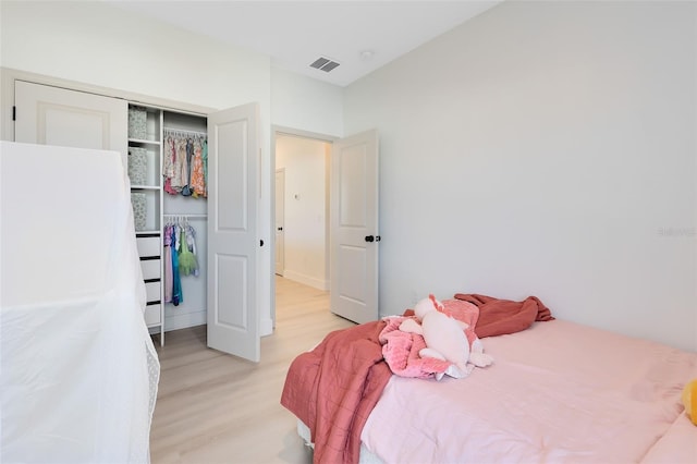 bedroom with light hardwood / wood-style floors and a closet