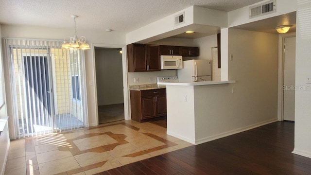 kitchen featuring white appliances, dark brown cabinetry, a textured ceiling, and light wood-type flooring