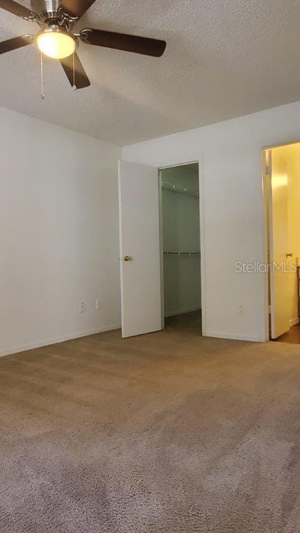 unfurnished room with ceiling fan, light carpet, and a textured ceiling