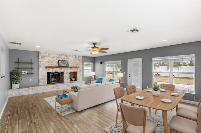 living room featuring a fireplace, light hardwood / wood-style floors, and ceiling fan