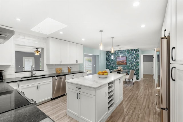 kitchen featuring a kitchen island, appliances with stainless steel finishes, white cabinetry, sink, and light hardwood / wood-style flooring