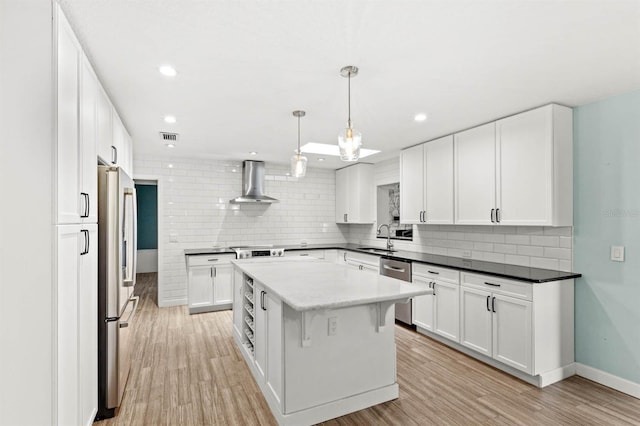 kitchen featuring sink, a center island, white cabinets, decorative light fixtures, and wall chimney exhaust hood