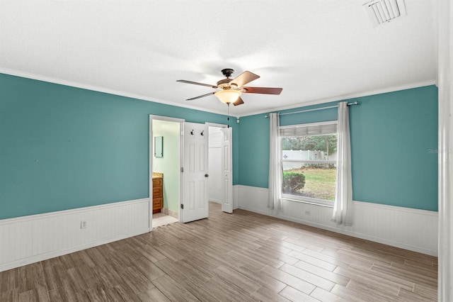 unfurnished bedroom featuring ceiling fan, ornamental molding, light hardwood / wood-style floors, and a textured ceiling