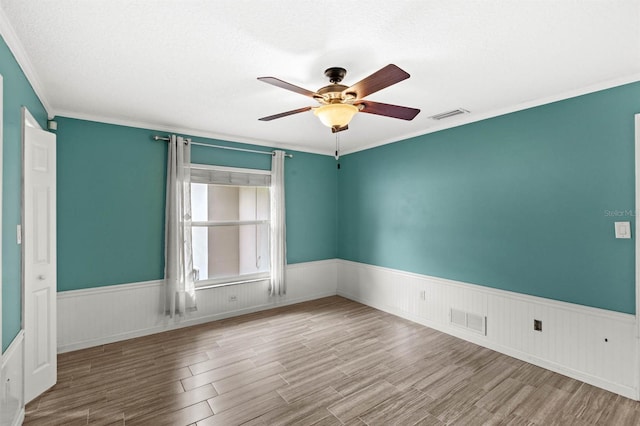 empty room featuring ornamental molding, hardwood / wood-style floors, a textured ceiling, and ceiling fan