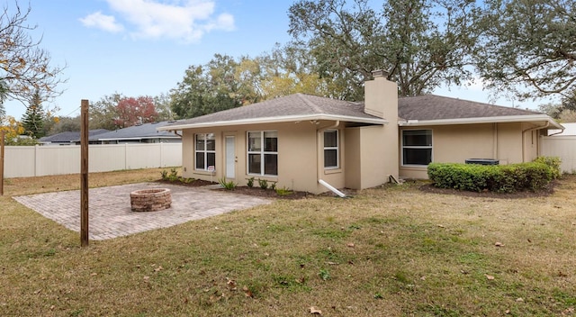 rear view of house with a patio, a yard, and a fire pit