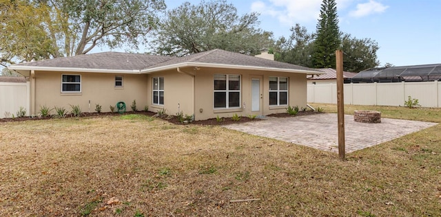 back of property with a yard, a patio area, and a fire pit