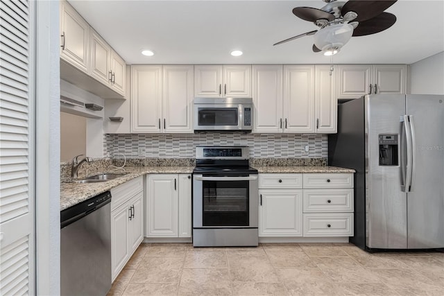 kitchen with sink, appliances with stainless steel finishes, white cabinets, light stone countertops, and backsplash