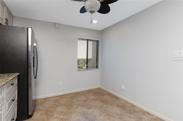 kitchen featuring light stone counters, ceiling fan, and stainless steel fridge with ice dispenser