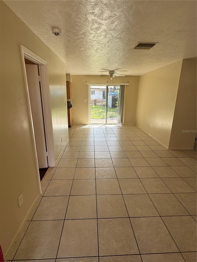 empty room featuring light tile patterned flooring, a textured ceiling, and ceiling fan