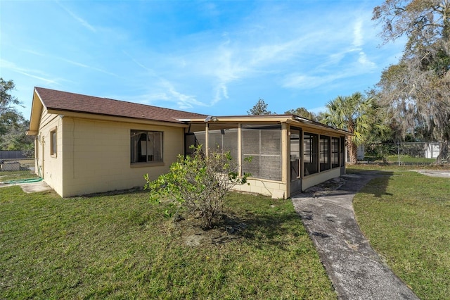 view of home's exterior with a lawn and a sunroom