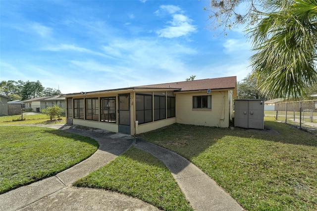 rear view of property featuring a sunroom and a lawn