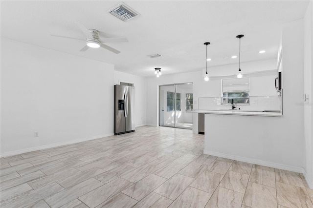 kitchen with stainless steel refrigerator with ice dispenser, white cabinetry, hanging light fixtures, ceiling fan, and backsplash