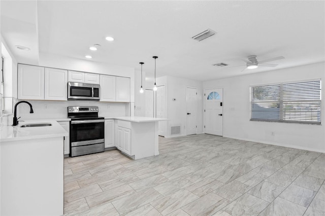 kitchen featuring sink, hanging light fixtures, kitchen peninsula, stainless steel appliances, and white cabinets