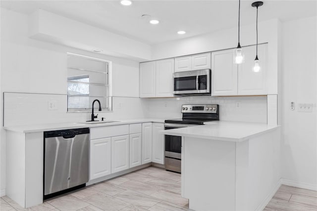 kitchen featuring sink, stainless steel appliances, white cabinets, decorative backsplash, and kitchen peninsula