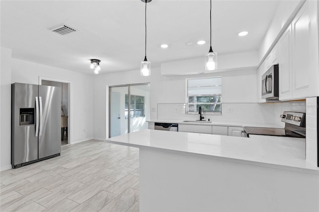 kitchen featuring hanging light fixtures, sink, kitchen peninsula, and appliances with stainless steel finishes