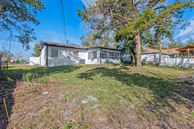 rear view of house featuring a yard and a sunroom