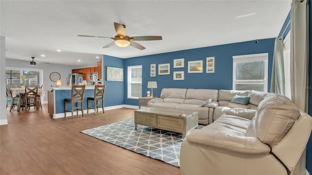 living room with ceiling fan, light hardwood / wood-style floors, and a textured ceiling